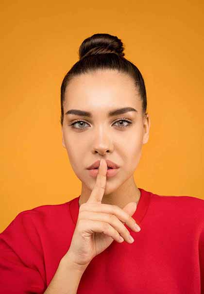 A photo of a Colombian woman wearing a red shirt, covering her lips with her right index finger