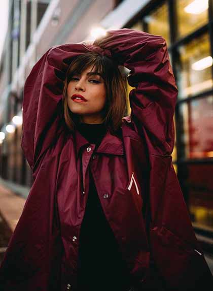 A Colombian woman in a maroon windbreaker fiercely staring at the camera.